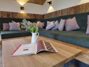 Wohnraum Flake mit Kissen, Blumen und Zeitschrift im Vordergrund